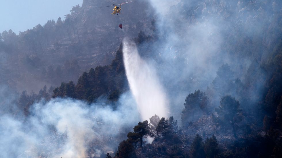 En helikopter som förra helgen släppte vatten över en skogsbrand nära Castellon de la Plana, i östra Spanien där bränderna nu är under kontroll. Arkivbild.