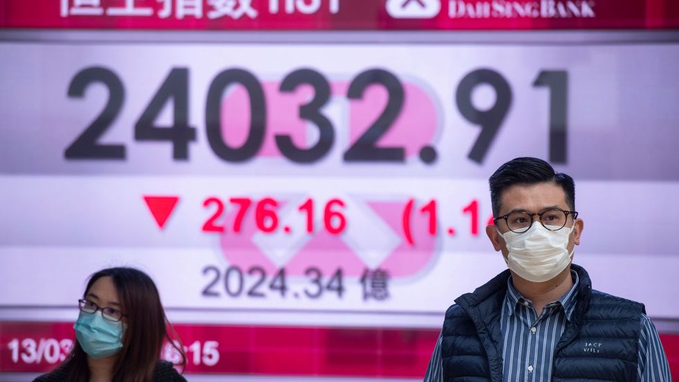 Hongkongbor vid en skärm som visar börsutvecklingen. Coronasmittan har fått aktiekurser världen över att rasa.