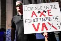 En man med ett plakat under en demonstration mot vaccinering.