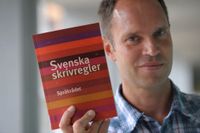 Ola Karlsson på Språkrådet håller upp 2008 års upplaga av ”Svenska skrivregler”.