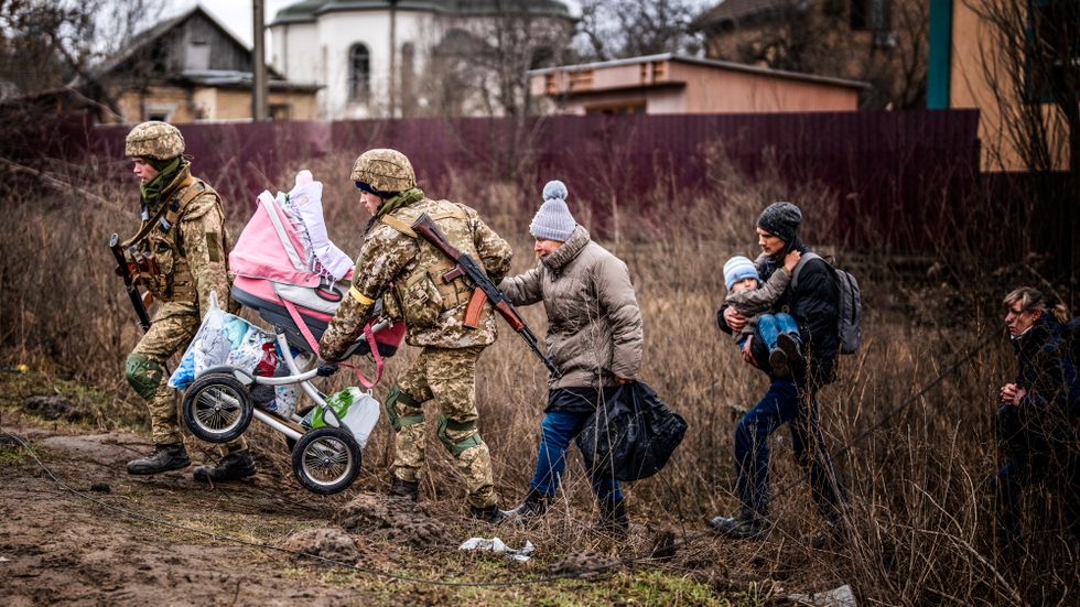Ukrainska soldater hjälper en barnfamilj i Irpin, strax utanför Kiev.