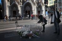 En kvinna tänder ett ljus utanför Notre Dame i Nice, dagen efter knivdådet som tog tre människors liv.