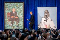 USA:s tidigare president Barack Obama och porträttet på honom av konstnären Kehinde Wiley när målningen presenterades 2018. Till höger det officiella porträttet på Michelle Obama. Arkivbild.