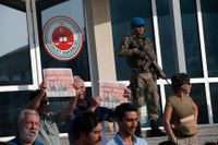 Demonstranter håller upp Cumhuriyets förstasida, med rubriken "Vi vill ha rättvisa", när rättegången mot 17 av tidningens journalister återupptas.