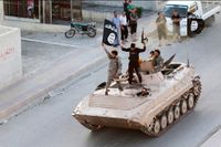 Soldater från terrorgruppen Islamiska staten på en gata i Raqqa i Syrien den 30 juni. De svartvita IS-fanorna vajar.