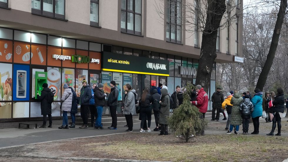 Människor köar för på torsdagsmorgonen att ta ut pengar i bankautomater i Kiev.