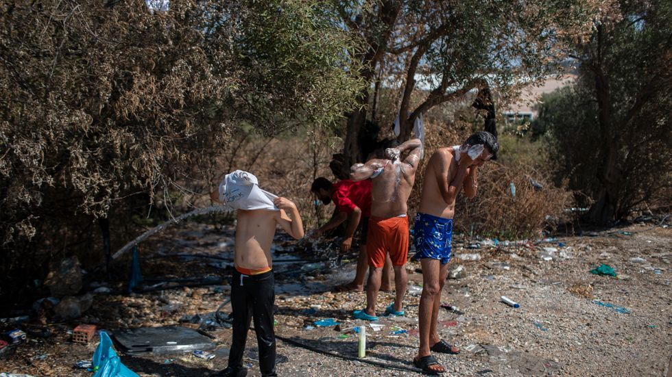Hemlösa migranter sköter sin hygien utanför det nedbrunna lägret Moria på Lesbos.