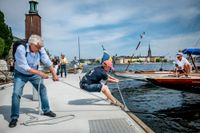 Många nyfikna samlas runt båtarna i den tillfälliga hamnen som byggt vid Norr Mälarstrand. Här får Skärgårdskryssaren "Bacchant", byggd 1936, hälp att lägga till vid kajen.