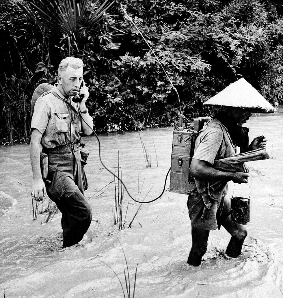 En inhemsk soldat bär den radioutrustning som en fransk officer använder för att meddela sin position nordost om Saigon 1951.