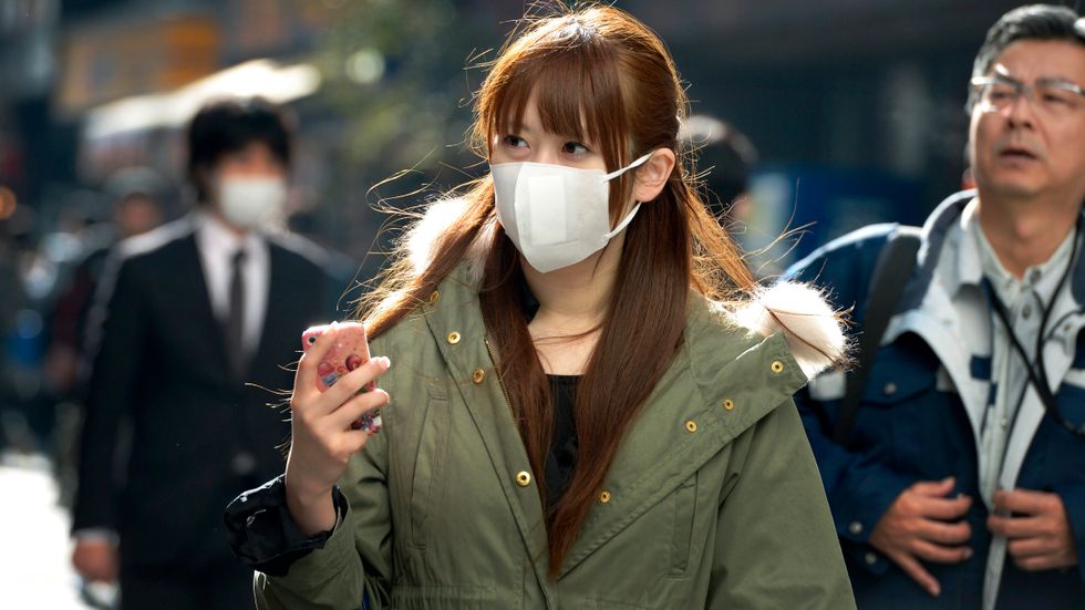 En ung kvinna i Tokyo bär munskydd. I Sverige har Apotekstjänst just nu slut på munskydd. 