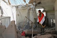 En soldat står med en syrisk flagga i ett förstört hus i Achan.