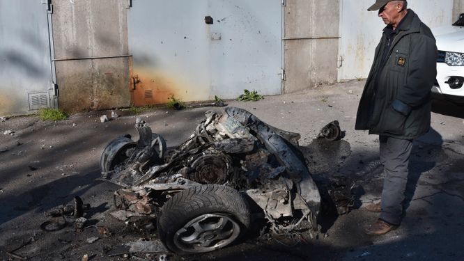 En man tittar på resterna av en bil som träffats av en rysk robotattack i Zaporizjzja öster om Kiev i Ukraina.