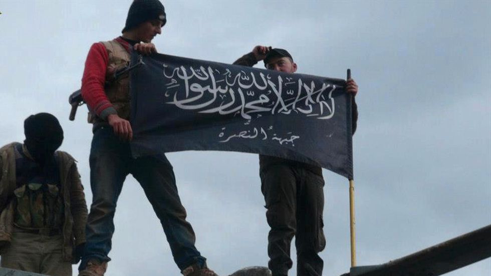 Anhängare till den terroriststämplade organisationen Jabhat al-Nusra håller upp en av organisationens flaggor på en flygbas i provinsen Idlib i Syrien. Bild från 2014.