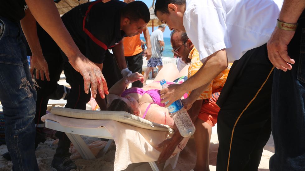 En kvinna vårdas på stranden i Sousse efter att en gärningsman öppnat eld. Minst 38 människor har dödats.