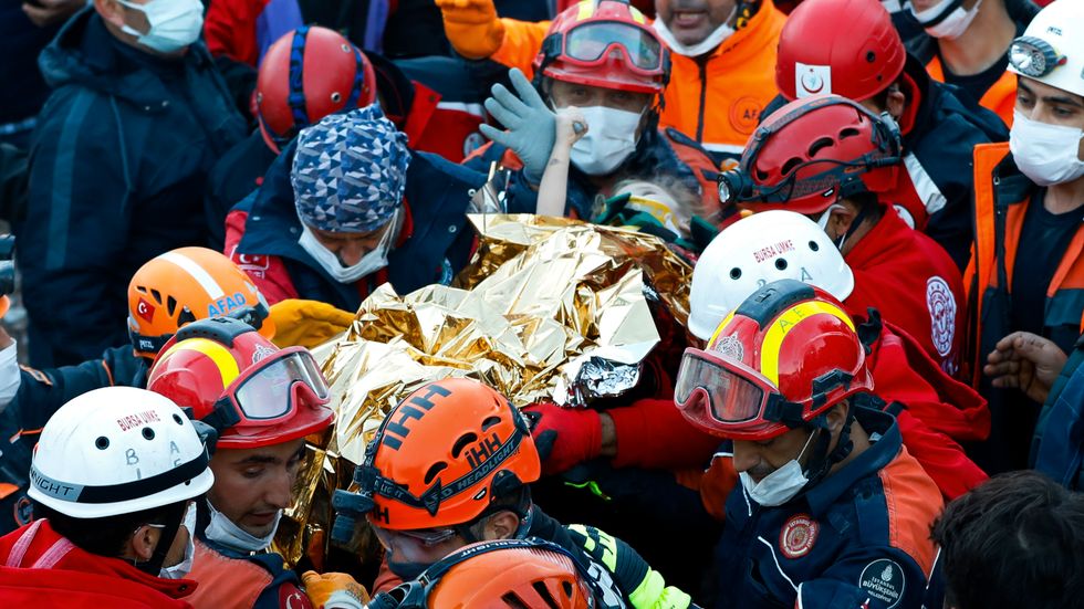 Räddningsarbetare bär en treårig flicka som grävts fram vid liv ur rasmassorna 65 timmar efter det dödliga skalvet.