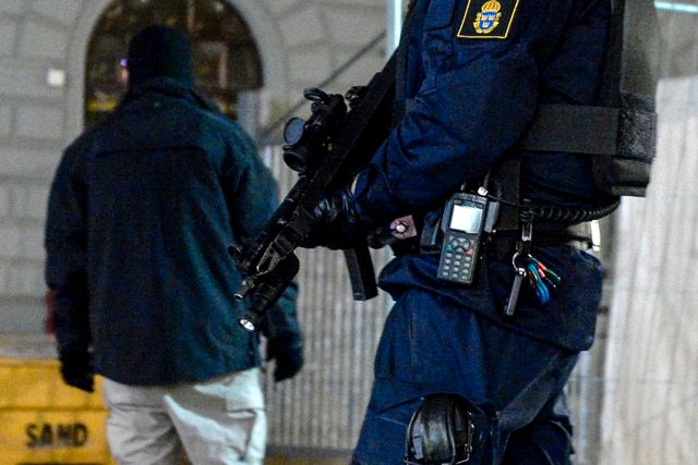 Polis med automatvapen utanför en judisk skola i Stockholm i februari i år. Poliser som bevakar judiska institutioner ska vara utrustade med automatgevär. Det framgår av polisens nya direktiv som tagits fram i syfte att öka säkerheten till följd av terrordåden i Köpenhamn.