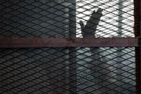 En medlem av Muslimska brödraskapet vinkar från försvarsfållan i en rättegång vid ett fängelse i Kairo. I höstas dömdes en stor grupp fångar till döden för att ha försökt fly från samma fängelse. Arkivbild.
