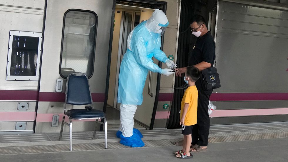 En sjukvårdare testar syrenivåerna på en covidsmittad som ska åka med tåg från Bangkok till sin hemstad. Syftet är att minska trycket på sjukvården i huvudstaden.