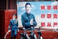 En kinesisk vakt framför ett porträtt av Xi Jinping vid entrén till den förbjudna staden i Peking.