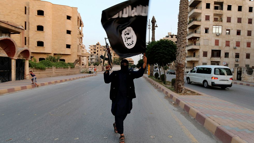 En Isis-medlem viftar med organisationens flagga i Raqqa i Syrien.
