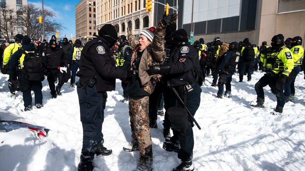 En demonstrant sjunger nationalsången "O Canada" medan han grips av polis i Kanadas huvudstad Ottawa.