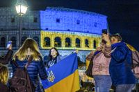 Människor samlade vid Colosseum i Rom som är upplyst i blått och gult till stöd för Ukraina.