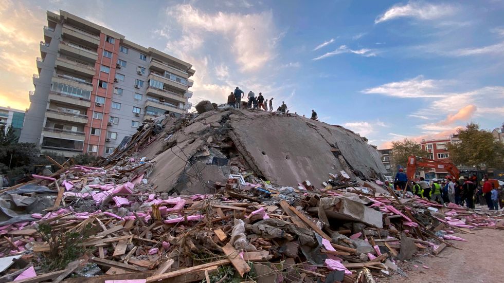 Räddningsarbetare letar efter överlevande i rasmassorna efter en byggnad som kollapsade i staden Izmir i Turkiet.