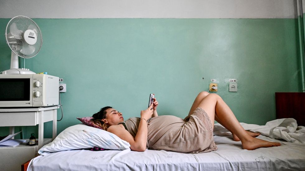 En gravid kvinna tittar på sin telefon på en avdelning på mödravårdskliniken i västra Zaporizjzja. Bilden togs den 1 september.