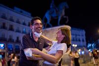 Ett par firar vid torget Puerta del Sol i Madrid efter det att munskyddskravet slopats vid midnatt, natten till den 26 juni.