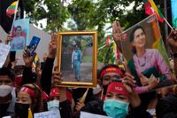 Myanmarier i Thailand håller upp bilder på den avsatta myanmariska ledaren Aung San Suu Kyi under en protest utanför Myanmars ambassad i Bangkok i juli.