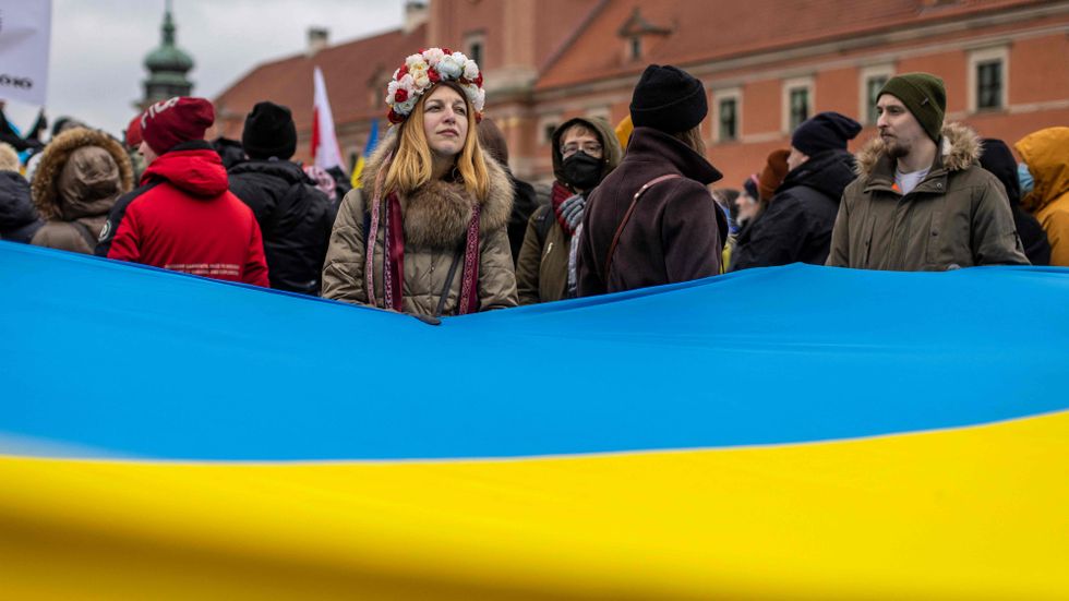 Demonstranter till stöd för Ukraina håller fram den ukrainska flaggan i Polens huvudstad Warszawa på söndagen.