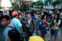 Människor samlas på gatan efter att ha utrymt en kontorsbyggnad i Manila i Filippinerna efter måndagens jordbävning.