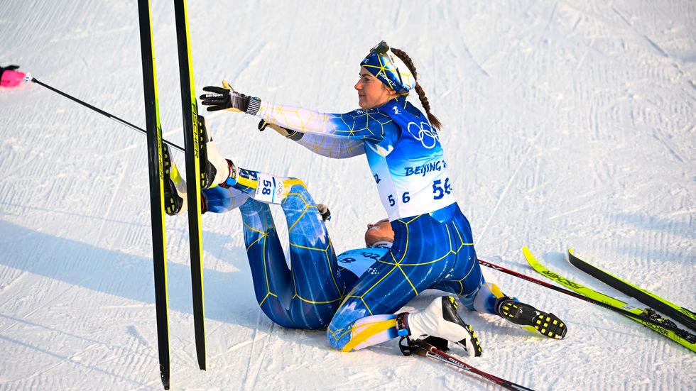 Frida Karlsson får hjälp av Ebba Andersson efter målgången i milloppet i OS.