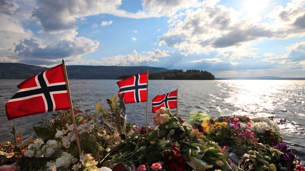Flaggor och blommor vid Sundvollen, med Utøya i bakgrunden. Arkivbild.