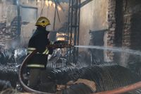 En brandman håller på att försöka släcka branden i skrotlagret i Hyderabad.