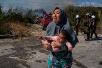 En kvinna som förlorat sitt hem i branden söker skydd undan sammandrabbningar mellan polis och migranter nära staden Mytilene, Grekland.