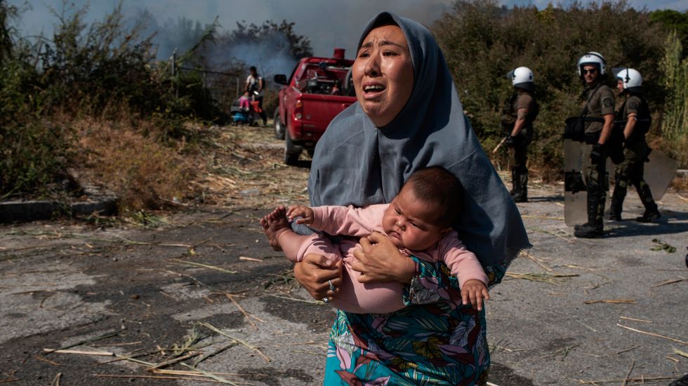En kvinna som förlorat sitt hem i branden söker skydd undan sammandrabbningar mellan polis och migranter nära staden Mytilene, Grekland.