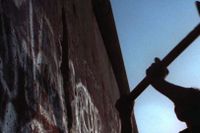 En man slår med slägga mot Berlinmuren, efter att gränsbarriären mellan öst och väst har upplösts efter 28 års tid. 