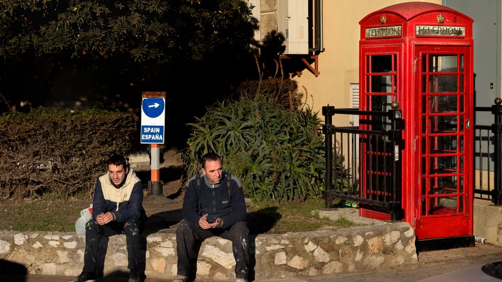Ett par spanska arbetare vid en typisk brittisk telefonkiosk i Gibraltar, som nära 300 000 människor på båda sidor gränsen är beroende av för sitt livsuppehälle.
