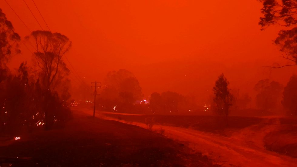 Byn Nerrigundah i södra New South Wales insvept i eld och rök. Bilden är tagen på nyårsafton förra året.