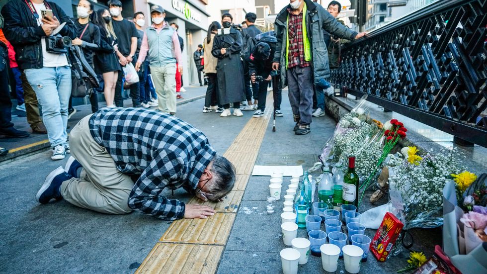 En man hedrar offren för lördagens halloweenfirande i Seoul, Sydkorea. Blomstermuren är nära den plats där tragedin inträffade.