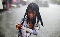 En flicka försöker hålla sig varm nära Manila i Filippinerna under det kraftiga ovädret i somras.