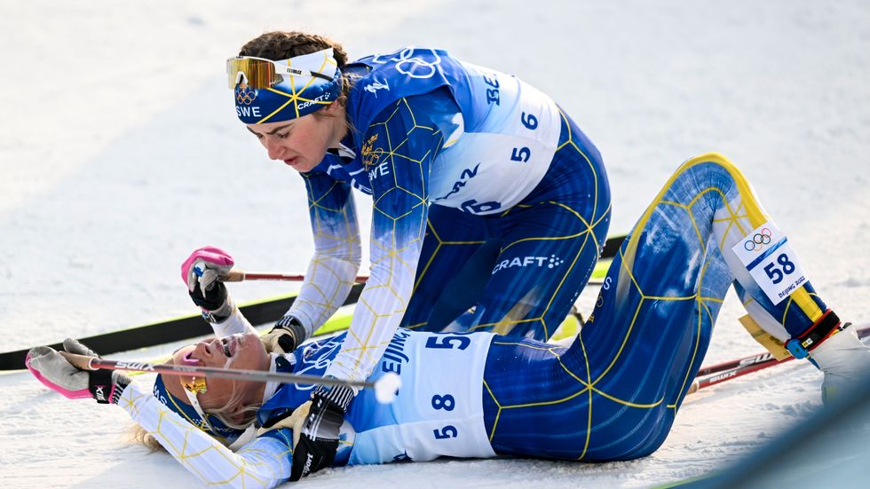 Ebba Andersson hjälper en utpumpad Frida Karlsson efter målgången på 10 kilometer.