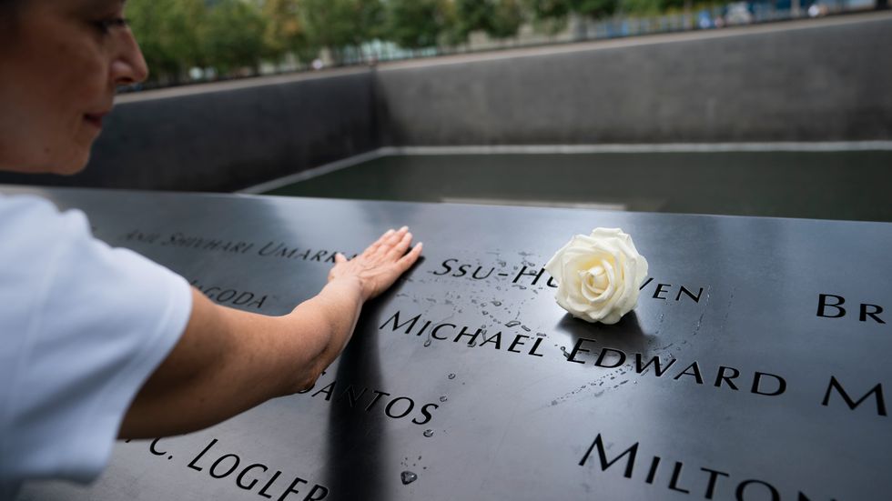En kvinna lägger en vit blomma vid minnesplatsen för offren av bombningen av World Trade Center 1993 och terrorattackerna den 11 september 2001 på nedre Manhattan i New York. Arkivbild.
