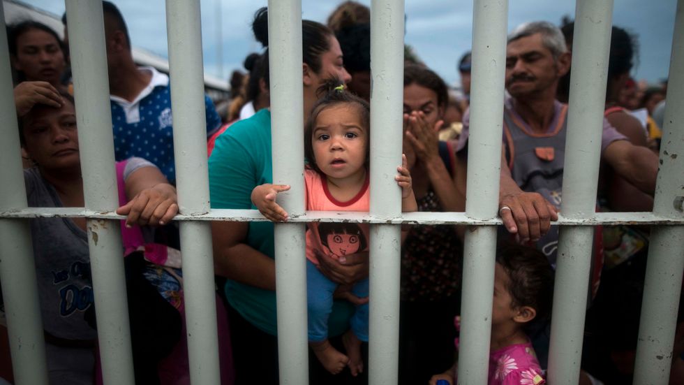  Migrants bound for the U.S.-Mexico border stand in front of a closed gate as they wait on a bridge that stretches over the Suchiate River, connecting Guatemala and Mexico, in Tecun Uman, Guatemala, on Friday, Oct. 19, 2018 
