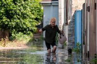 En ukrainsk kvinna vadar fram sedan Kachovkadammen förstörts och flera samhällen drabbats av översvämning.
