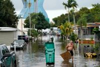 Invånare i Davie, i södra Florida, plockar upp bråte från en översvämmad gata efter att den tropiska stormen Eta dragit förbi, på tisdagen.