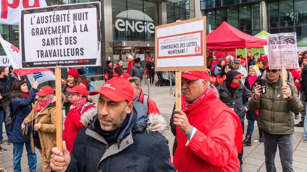 "Åtstramningarna skadar allvarligt arbetarnas hälsa", står det på skylten hos strejkande demonstranter utanför energibolaget Engies kontor i Bryssel under onsdagens nationalstrejk.