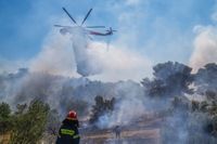 En brand i östra Aten vattenbombas av helikopter, onsdagen den 20 juli.