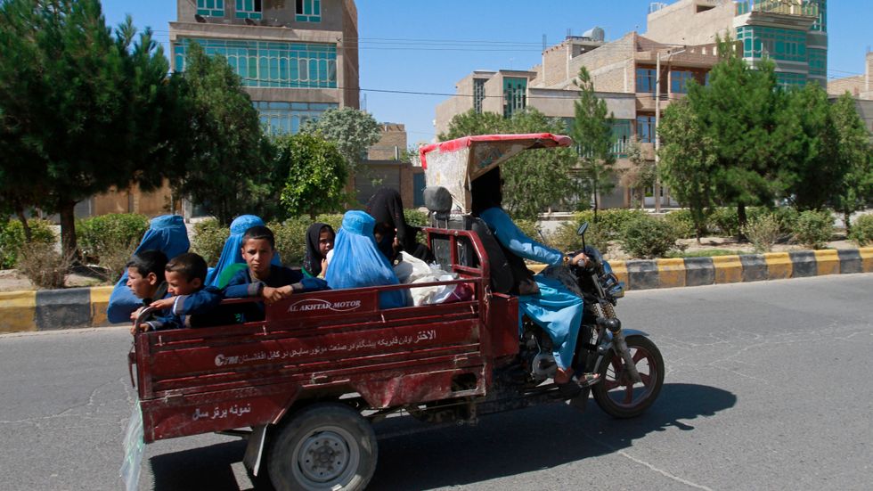 Afghanska kvinnor och barn färdas på en gata i provinshuvudstaden Herat på söndagen medan talibanerna rycker fram mot staden under strider med den afghanska armén.